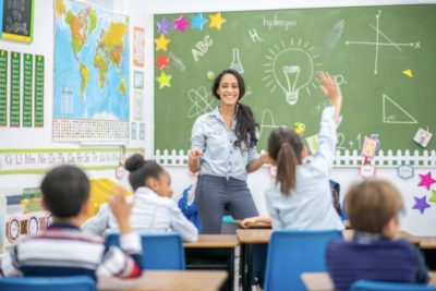 A teacher stands at the front of a class full of students.